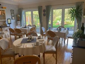 un restaurante con mesas y sillas blancas y ventanas en Dungimmon House, en Ballyconnell