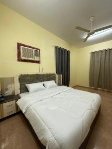 a bedroom with a large white bed with a ceiling fan at Blossoms hills apartment in Samhān