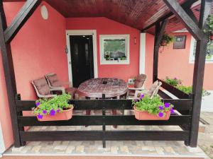 a red house with a table and chairs and flowers at BANJANSKI RAJ in Arandjelovac