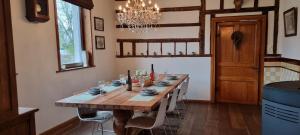 une salle à manger avec une table en bois et un lustre dans l'établissement Gite L'éternité, à Heure