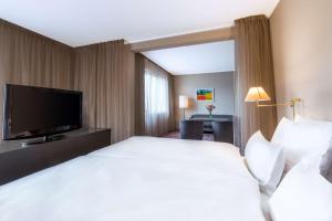 a hotel room with a bed and a flat screen tv at NH Collection Prague in Prague