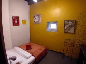 a small room with a bed with a yellow wall at Manoir du Boscau, Gilles del Bosc in Prudhomat