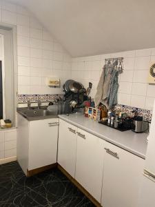 una cocina con armarios blancos y fregadero en Incredibly spacious King size Room with full Main Floor of the Flat!, en Oxford