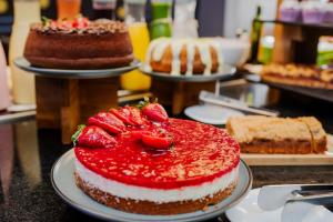 a cake with strawberries on a counter with other cakes at ibis Styles Sao Jose do Rio Preto in Sao Jose do Rio Preto