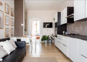 ein Wohnzimmer mit einem schwarzen Sofa und einer Küche in der Unterkunft Chiarilù near the center Politecnico Fair and City Life in Mailand