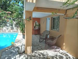 un patio con 2 sillas y una piscina en Villa rozenuda en Boca Chica