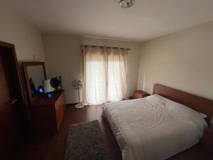 1 dormitorio con cama blanca y ventana en Casa Rosa Aluguel de Quartos, en Calvão