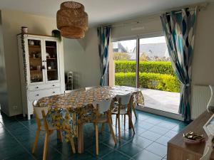 ein Esszimmer mit einem Tisch, Stühlen und einem Fenster in der Unterkunft L'olivier du Cabellou, à 900 m des plages in Concarneau