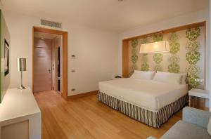 a bedroom with a white bed and a lamp at NH Firenze in Florence