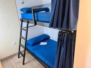 Litera con almohadas azules y escalera en Pensión KM73 CAMINO PRIMITIVO Ferreira - Lugo, en Palas de Rei 