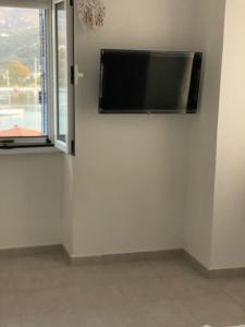a flat screen tv hanging on a wall next to a window at Aggeliki Homes paradosiako nisiotiko in Poros