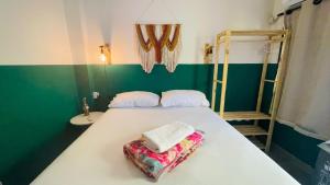 a bedroom with a white bed with a green wall at Sunflower Hostel in Salvador