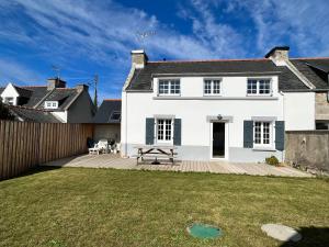 ein weißes Haus mit einer Holzterrasse im Garten in der Unterkunft Kelerdutbay fr, accès direct à la mer in Plouguerneau