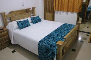 1 dormitorio con 1 cama grande con almohadas azules en HotelSueño Dorado Aguadas, en Aguadas