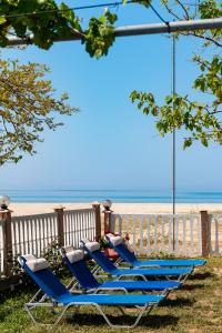 a row of blue lounge chairs on the beach at Lampiris Beach Front Apartments in Potos