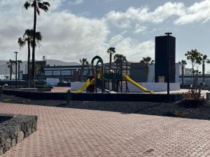 un parque infantil con tobogán en un parque con palmeras en Las Brisas, Villa 98 en Playa Blanca