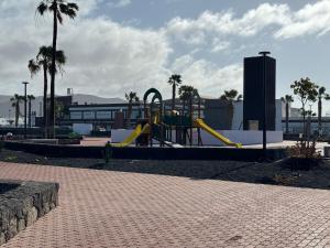 a playground with a slide in a park with palm trees at Las Brisas, Villa 98 in Playa Blanca
