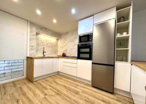 uma cozinha com armários brancos e um frigorífico de aço inoxidável em Exclusivo Apart. Frente al Mar em Salou