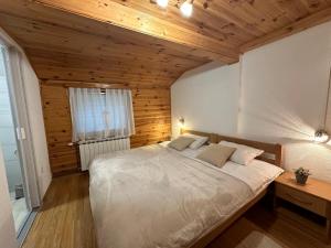 a large bed in a room with a wooden ceiling at Guest house Zeder in Jezerce