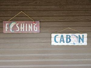 dois sinais estão pendurados numa parede de madeira em Glamper's Dream - Lakefront Cabin with Mountain View em Clayton