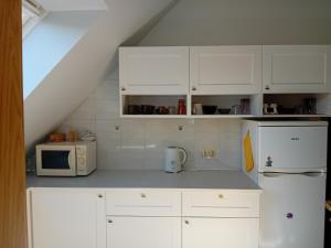 a kitchen with white cabinets and a microwave at Pokoje u Igi in Gdańsk