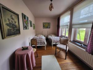 Cette chambre comprend deux lits, une table et des chaises. dans l'établissement Charming and cosy ART DECO house in old historic farm with private natural pool and gardens with hiking and cycling trails nearby, à Saint-Trond