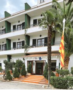 un bâtiment avec drapeau et palmier dans l'établissement Hotel Gri-Mar, à Llançà
