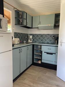 a kitchen with white cabinets and blue appliances at Chalet T3 4/6 personnes à Agde in Agde
