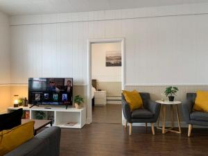 uma sala de estar com duas cadeiras e uma televisão em Large 1-bedroom Condo l Downtown l WiFi & Smart TV em Moose Jaw
