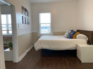 um quarto com uma cama grande e 2 janelas em Large 1-bedroom Condo l Downtown l WiFi & Smart TV em Moose Jaw