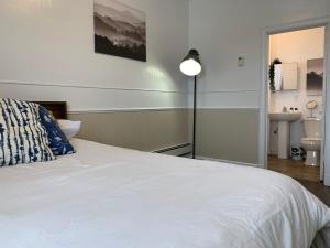 a bedroom with a white bed with a lamp and a sink at Large 1-bedroom Condo l Downtown l WiFi & Smart TV in Moose Jaw