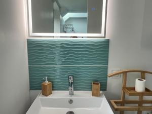 ein Badezimmer mit einem Waschbecken und einem Spiegel darüber in der Unterkunft Kelerdutbay fr, accès direct à la mer in Plouguerneau