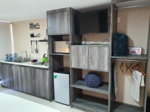 een keuken met houten kasten, een tv en een koelkast bij S55 SUITE DE LUJO CON TODO LO NECESARIO A 5 MIN ITESM CEM in Mexico-Stad