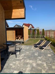 eine Terrasse mit Stühlen, einem Tisch und Stühlen in der Unterkunft Klimatyzowany domek letniskowy in Mielno