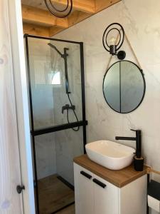 ein Bad mit einem Waschbecken und einer Dusche mit einem Spiegel in der Unterkunft Klimatyzowany domek letniskowy in Mielno