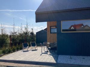 eine Terrasse mit Stühlen, einem Tisch und einem Gebäude in der Unterkunft Klimatyzowany domek letniskowy in Mielno