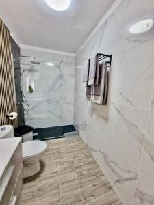 a white bathroom with a toilet and a shower at RockBeach bungalow in Costa Teguise