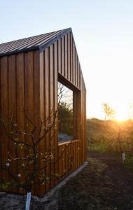 un pequeño edificio de madera con una ventana y un árbol en Căsuța din livadă, en Măneciu