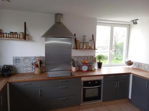 a kitchen with gray cabinets and a stove top oven at Petite maison près de Disneyland in Magny-le-Hongre
