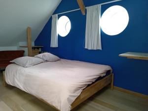 a blue bedroom with a bed with two windows at Petite maison près de Disneyland in Magny-le-Hongre
