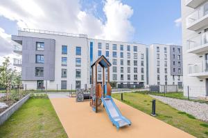 plac zabaw ze zjeżdżalnią przed budynkiem w obiekcie Glow Apartments, Letnica - Apartamenty Przystań Siódme Niebo w Gdańsku