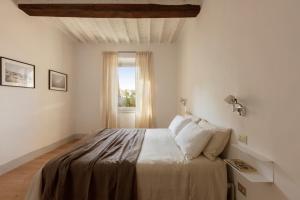 a white bedroom with a bed with a window at Umberto 121 in Montisi