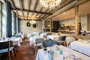 a restaurant with white tables and chairs and a chandelier at Hotel Biskajer by CW Hotel Collection in Bruges