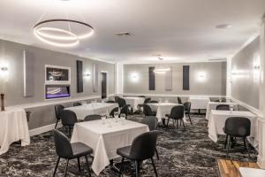 uma sala de jantar com mesas e cadeiras brancas em Inn on the Square, Ascend Hotel Collection em Greenwood