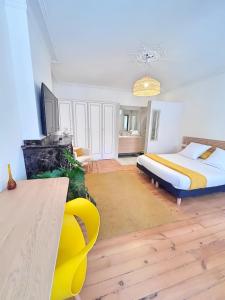 a bedroom with a bed and a yellow chair in it at L'Elegant Paradoux - 3 sdb - 2 wc - Ascenseur - Parking - Plein Centre in Toulouse