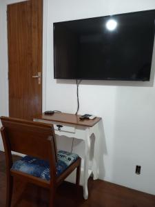 Zimmer mit einem Schreibtisch und einem großen TV an der Wand in der Unterkunft Pousada Harmonia Pomerana in Pomerode
