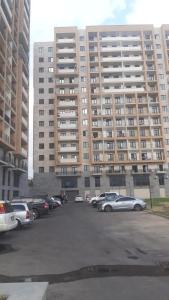 parking z samochodami zaparkowanymi przed dużym budynkiem w obiekcie Kvartira dizaynerskaya w Erywaniu