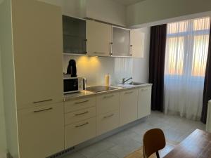 a kitchen with white cabinets and a sink and a microwave at For5 in Đakovo