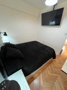 1 dormitorio con cama negra y TV de pantalla plana en Departamento único en San Telmo en Buenos Aires
