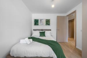 um quarto branco com uma cama grande e um cobertor verde em Stylish 1BR Retreat at Station House Milton Keynes em Milton Keynes